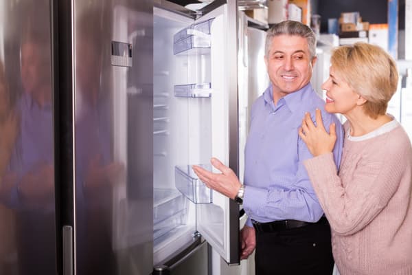 A mature woman and man inspecting a refrigerator A mature woman and man inspecting a refrigerator